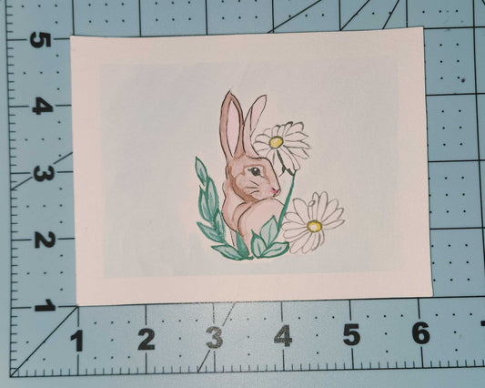 Small card with a rabbit and flower design on a cutting mat.