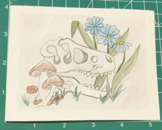 Card with a skeleton hand holding flowers on a green cutting mat