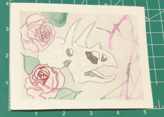 Artistic drawing of a Dinosaur with flowers on a green cutting mat.