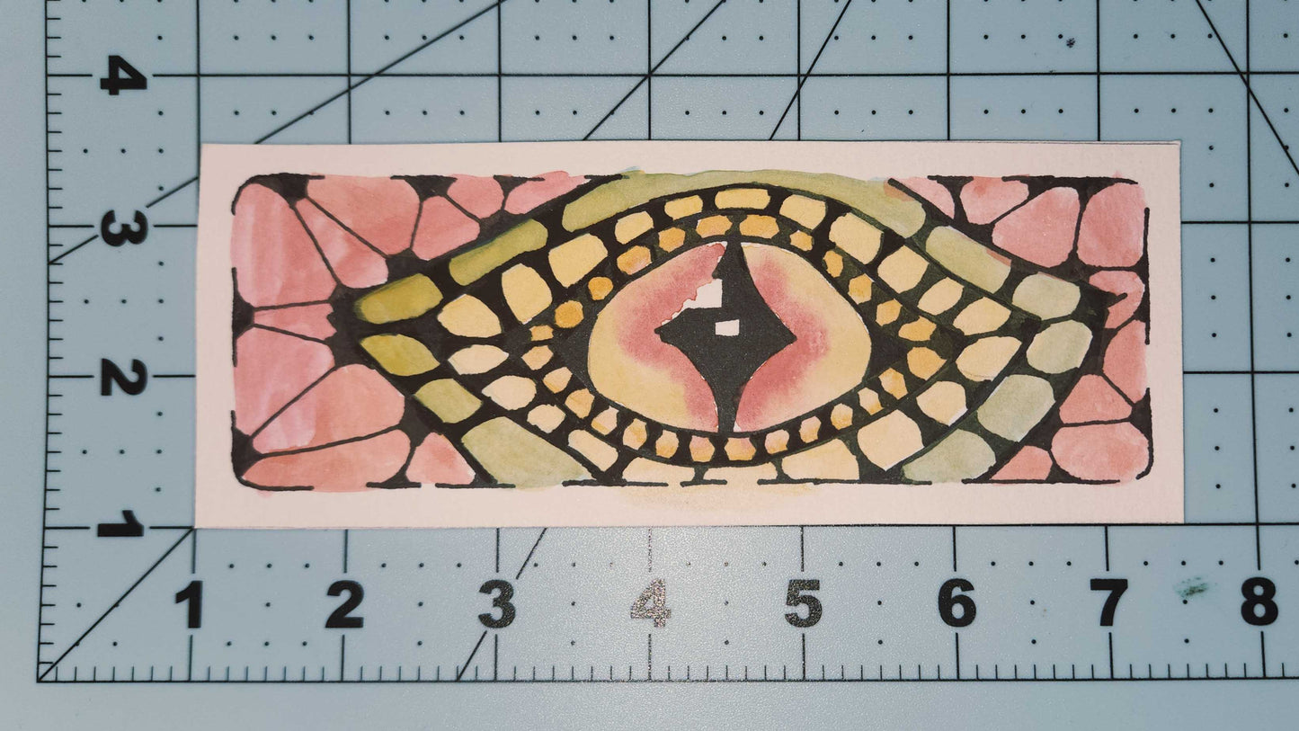 Decorative rectangular bookmark with a colorful pattern on a cutting mat with measurements.