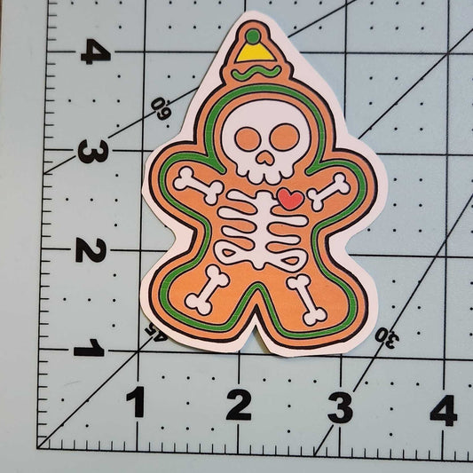 Gingerbread skeleton cookie with a skull design on a cutting mat with grid lines.