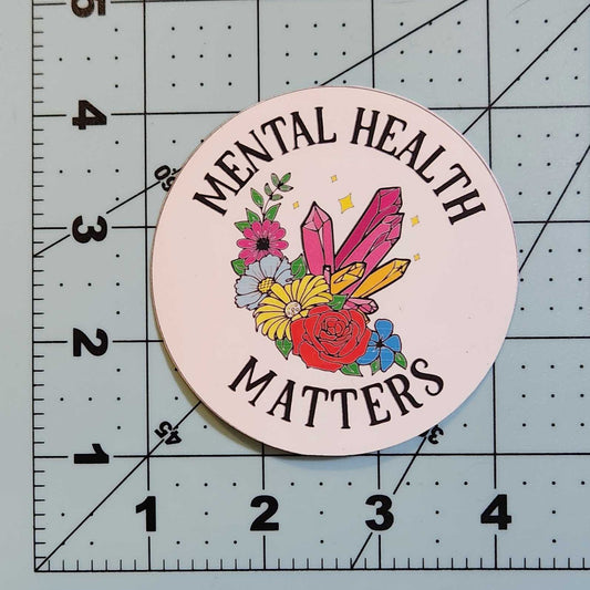 Circular sticker with floral design and text on a cutting mat
