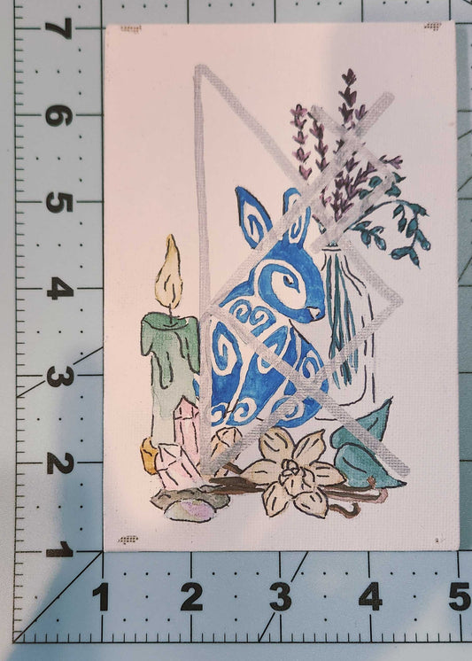 Decorative paper cutout with a blue bunny and flowers on a white background, measured against a ruler.