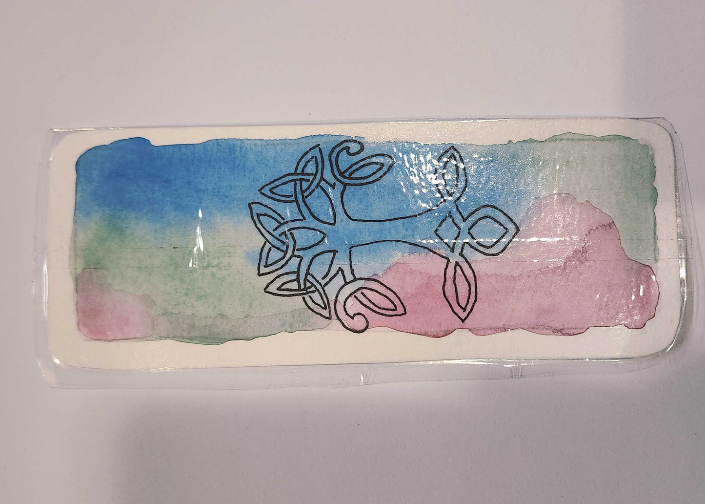 Decorative rectangular object with Celtic knot design on a colorful background