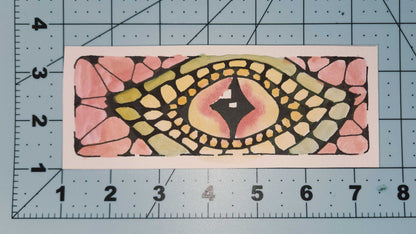 Decorative rectangular bookmark with a colorful pattern on a cutting mat with measurements.