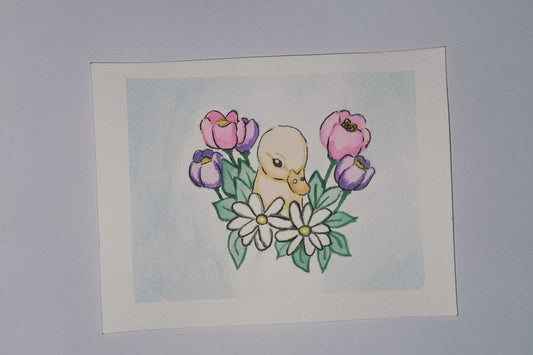 Card with a duck and flowers on a light blue background, next to a ruler.